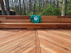 a wooden bench with a green towel on it's back and trees in the background