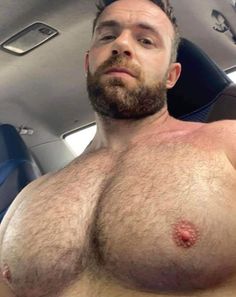 a man with no shirt on sitting in a car