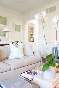 a living room filled with furniture and a large flower vase on top of a coffee table