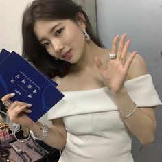 a woman in a white dress holding up a blue book