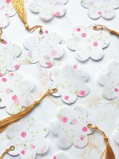 some paper flowers and tassels on a white table with gold trim around them