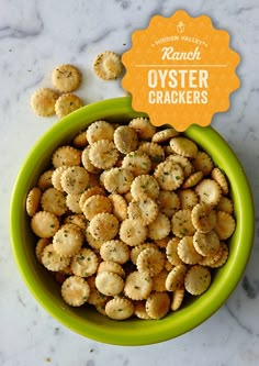 a green bowl filled with crackers on top of a white counter next to a sign that says ranch oyster crackers