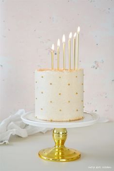 a white cake with gold polka dots and candles