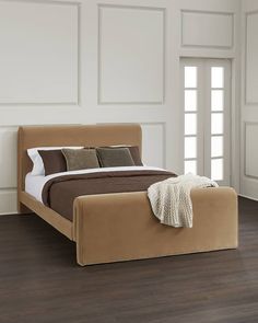 a large bed sitting on top of a wooden floor next to a white wall and window