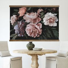 a table with two chairs and a vase on it in front of a floral painting