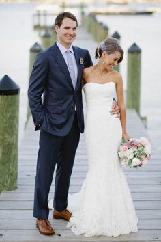 a bride and groom standing on a dock