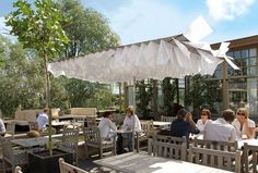 people are sitting at tables under an umbrella