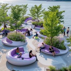 several people sitting on purple couches in front of the water and trees, while others are