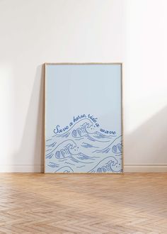 an empty frame on the floor in front of a wall with a blue ocean print