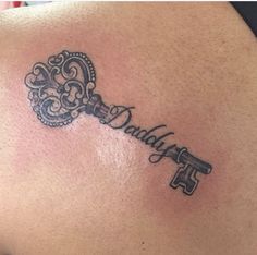 a key tattoo on the back of a woman's shoulder