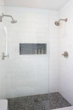 a white tiled bathroom with glass shower doors