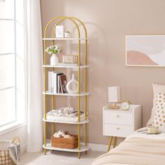 a bedroom with pink walls and white furniture, including a gold metal shelving unit