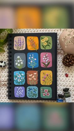 a notebook with flowers on it sitting next to some pine cones and other things around