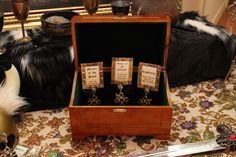 an open wooden box with three pairs of earrings in it sitting on a table next to other items