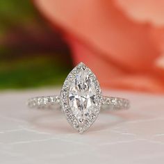 a close up of a diamond ring on a table with flowers in the back ground