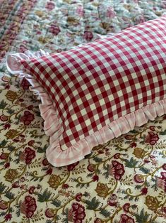 a red and white checkered pillow sitting on top of a bed