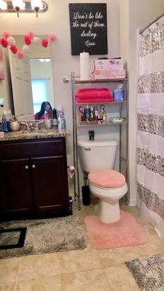 a bathroom with a toilet, shower curtain and pink rugs on the floor in front of it