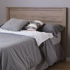 a bed with gray sheets and pillows in a bedroom