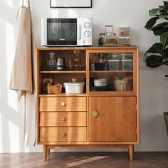 a wooden cabinet sitting next to a potted plant on top of a hard wood floor