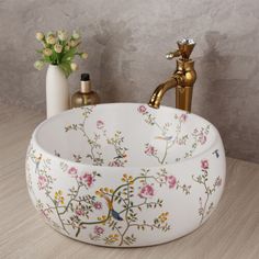 a bathroom sink with flowers painted on the bowl and faucet next to it