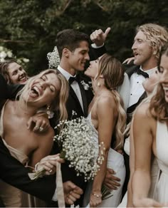 a group of people standing next to each other in front of some trees and flowers