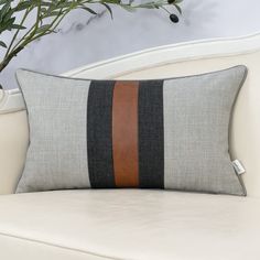 a white couch with a brown and black striped pillow on it's backrest