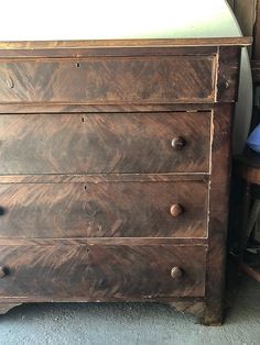 an old chest of drawers with knobs on the top and bottom, next to a chair