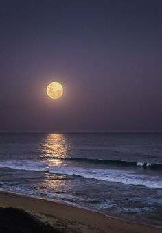 the full moon is shining over the ocean