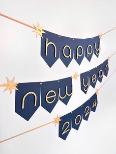 two blue and gold happy new year banners hanging on a string with star garlands