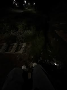 the person is sitting in the dark with their feet on the ground at night time