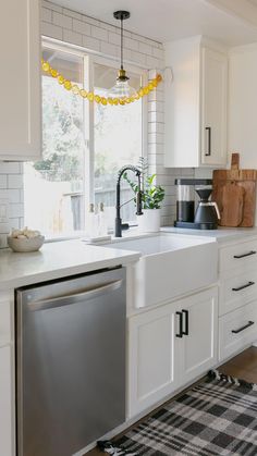 a kitchen with white cabinets and stainless steel dishwasher in the center, next to a black and white checkered rug