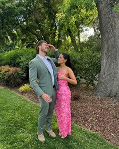 a man standing next to a woman in a pink dress