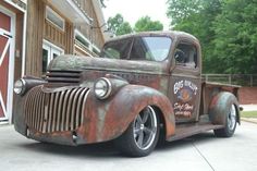 an old rusted truck parked in front of a garage