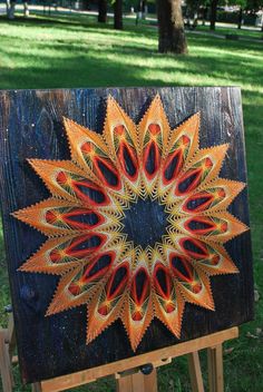 a wooden easel with an orange and yellow flower painted on the side in front of it