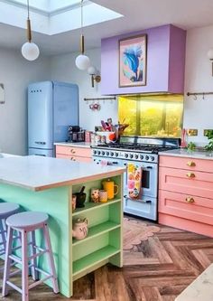 a kitchen with pink, blue and green cabinets and an island in front of the stove