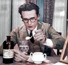 a man sitting at a table in front of a bottle of wine with a spoon