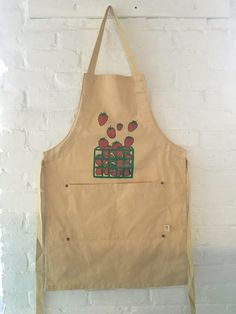 an apron hanging on the wall with strawberries painted on it's front and back