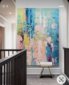 an abstract painting hangs on the wall next to a banister in a modern home