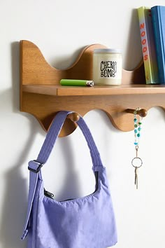 a purple purse hanging on a wooden shelf next to a book and key rack with books