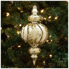 an ornament hanging from a christmas tree in front of a lite - up evergreen