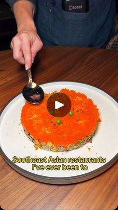 a person is cutting into a cake on a white plate with an orange frosting