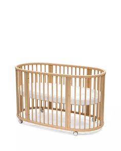 a wooden baby crib with white sheets on the sides and wheels, against a white background