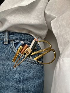 a pair of scissors and pencils sticking out of the back pocket of someone's jeans