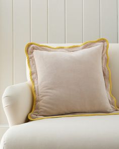 a white chair with a yellow trim around the cushion and pillow on top of it