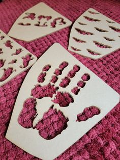 four cut out pieces of paper sitting on top of a pink blanket with holes in the middle