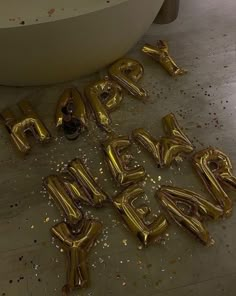 gold foil balloons that spell out the word happy new year in front of a bathtub