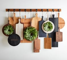 wooden cutting boards hanging on a wall with potted plants next to them and personalized cutting boards