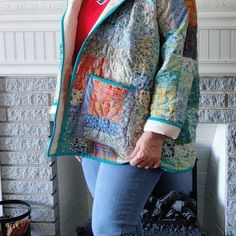 a woman standing in front of a fire place wearing a jacket with patches on it