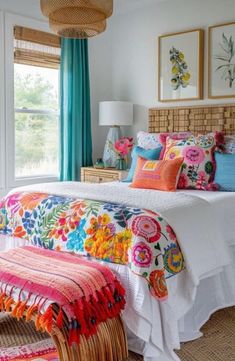 a bed with colorful pillows and blankets in a bedroom next to a window filled with blue curtains