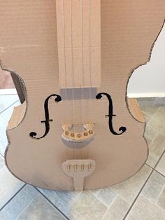 an old violin is sitting on the floor in front of a cardboard box that has been taped to it